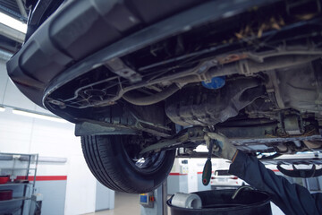 Car mechanic checks car on lift on Service station.