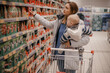 Mother and child buying in supermarket. Mom and her little son are in a grocery store shopping for food.