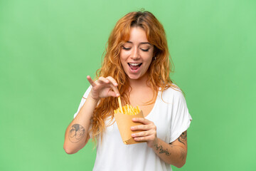 Wall Mural - young caucasian woman holding fried chips isolated on green screen chroma key background