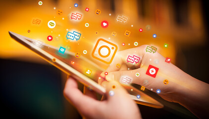 Close-up of a hand using tablet with social media icons