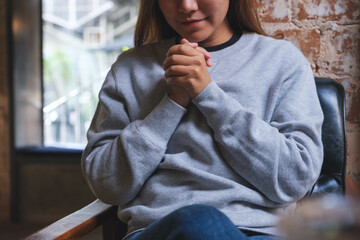 Wall Mural - Closeup image of a woman with holding hands while thinking, praying or making decision