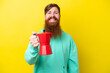 © luismolinero - Redhead man with beard holding coffee pot isolated on yellow background with happy expression