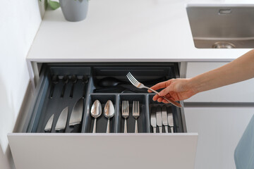 Wall Mural - woman taking fork from drawer with cutlery at kitchen