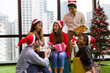 © amorn - Group of happy young man and woman giving Christmas gift box on Christmas party day at night. Merry Christmas and Happy Holidays