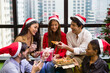© amorn - Group of happy young man and woman giving Christmas gift box on Christmas party day at night. Merry Christmas and Happy Holidays