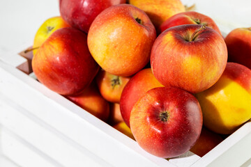 Wall Mural - Natural, farm red apples in a white wooden box on a white background. Selling seasonal, local fruits and vegetables. Closeup