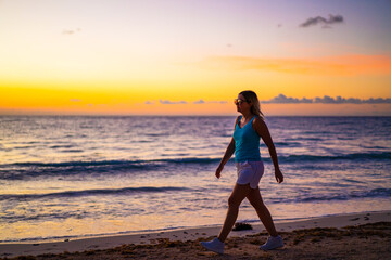 Wall Mural - Woman walking on sunny, tropical beach at daybreak
