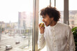 © jessica - Young man in the  office, eating an apple during a break in front of the window