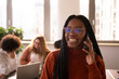 © jessica - Young, African woman in the office is using phone
