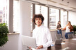 © jessica - Young man in the office, in foreground looking at the camera with his laptop