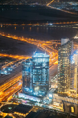 Wall Mural - Aerial view of evening night illuminations scenic view of skyscraper in Dubai. Street night traffic in Dudai skyline. Urban background of Dubai, UAE, United Arab Emirates. Vertical High quality photo.
