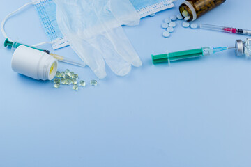 Wall Mural - Medical essentials: Masks, gloves, pills, and syringes on a blue surface, symbolizing health and safety.