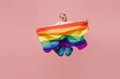 Full body fun young gay man wear sweatshirt hat hold striped rainbow flag jump high look camera scream shout isolated on plain pastel light pink color background studio. Lifestyle lgbtq pride concept.