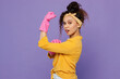 © ViDi Studio - Young fun woman wear yellow shirt rubber gloves while do housework tidy up show hand biceps muscles demonstrate strength power isolated on plain pastel light purple background . Housekeeping concept.