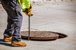 © Susan Vineyard  - Man removing or replacing a heavy manhole cover in paved street with hook - selective focus and copy space