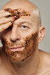 © TrueFrame Collective - Vertical studio beauty portrait of Caucasian adult man applying face scrub looking at camera, peeling