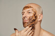 © Clique Images - Caucasian man gently rubbing his face with organic coffee grounds scrub horizontal beauty portrait