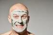 © Clique Images - Horizontal studio portrait of playful man with blue clay mask on face grimacing