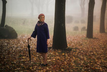 A Woman With An Umbrella, Standing In The Square In Foggy Weather.
