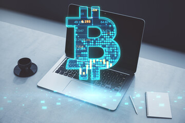 Wall Mural - Close up of laptop, coffee cup and notepad on desktop with glowing bitcoin hologram on blurry background. Cryptocurrency, finance and blockchain concept. Double exposure.