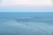 Scneic view of the open sea and the horizon under the light pink evening sky