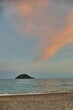 Vertical shot of turtle-shaped Gallinara island from the beach during the sunset in Liguria, Italy