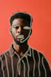© Clique Images - Vertical through glass with lining drawing portrait shot of stylish young Black man standing against coral wall background looking at camera