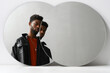 © Clique Images - Horizontal contemporary two mirrors reflection portrait of stylish young African American man wearing leather jacket looking at camera, copy space