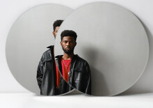 Horizontal Contemporary Creative Studio Two Mirrors Reflection Portrait Of Stylish Young Black Man Wearing Leather Jacket Looking At Camera