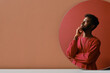 © TrueFrame Collective - Vertical creative mirror reflection studio portrait shot of stylish young African American man wearing coral pink sweatshirt thinking of something, copy space