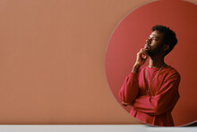 Vertical Creative Mirror Reflection Studio Portrait Shot Of Stylish Young African American Man Wearing Coral Pink Sweatshirt Thinking Of Something, Copy Space