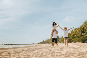 Wall Mural - Family day. Happy family people having fun in summer vacation run on beach, daughter riding on father back and mother running at sand beach, family trip playing together outdoor, traveling in holiday