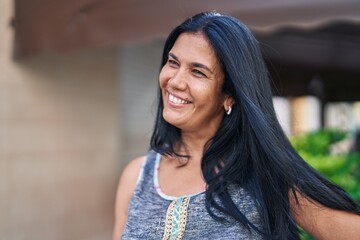 Wall Mural - Middle age hispanic woman smiling confident looking to the side at street