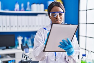 Sticker - Young african american woman scientist writing on document at laboratory