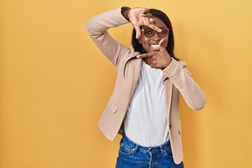 Wall Mural - African young woman wearing glasses smiling making frame with hands and fingers with happy face. creativity and photography concept.