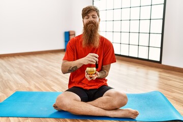 Wall Mural - Young redhead man training yoga at sport center