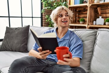 Poster - Young blond man reading book and drinking coffee at home