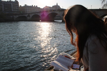 Girl reading along Seine river in Paris