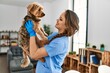 Young beautiful hispanic woman veterinarian smiling confident holding dog at home