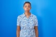 © Krakenimages.com - African american woman standing over blue background puffing cheeks with funny face. mouth inflated with air, crazy expression.