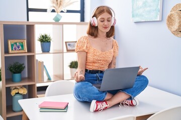 Poster - Young redhead woman sitting on table doing yoga exercise at home