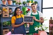 Young hispanic couple working at florist with open sign winking looking at the camera with sexy expression, cheerful and happy face.