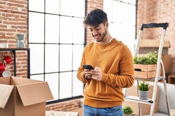 Canvas Print - Young hispanic man smiling confident using smartphone at new home