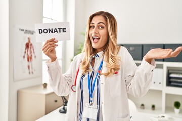 Sticker - Young blonde doctor woman supporting organs donations celebrating achievement with happy smile and winner expression with raised hand