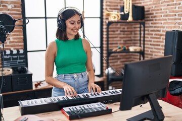 Poster - Young hispanic woman musician playing piano keyboard at music studio