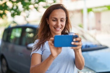 Wall Mural - Young woman smiling confident using smartphone at street