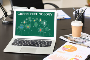 Wall Mural - Laptop with text GREEN TECHNOLOGY on screen in office