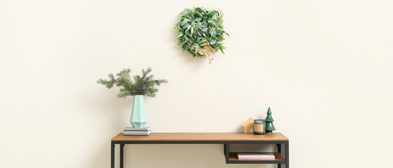 Wall Mural - Table with fir branches in vase, Christmas decor and mistletoe wreath in light room