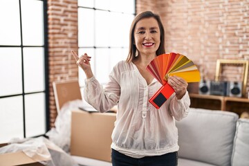 Sticker - Middle age hispanic woman choosing color of new house wall smiling happy pointing with hand and finger to the side