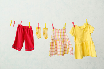 Wall Mural - Different baby clothes hanging on rope against light background